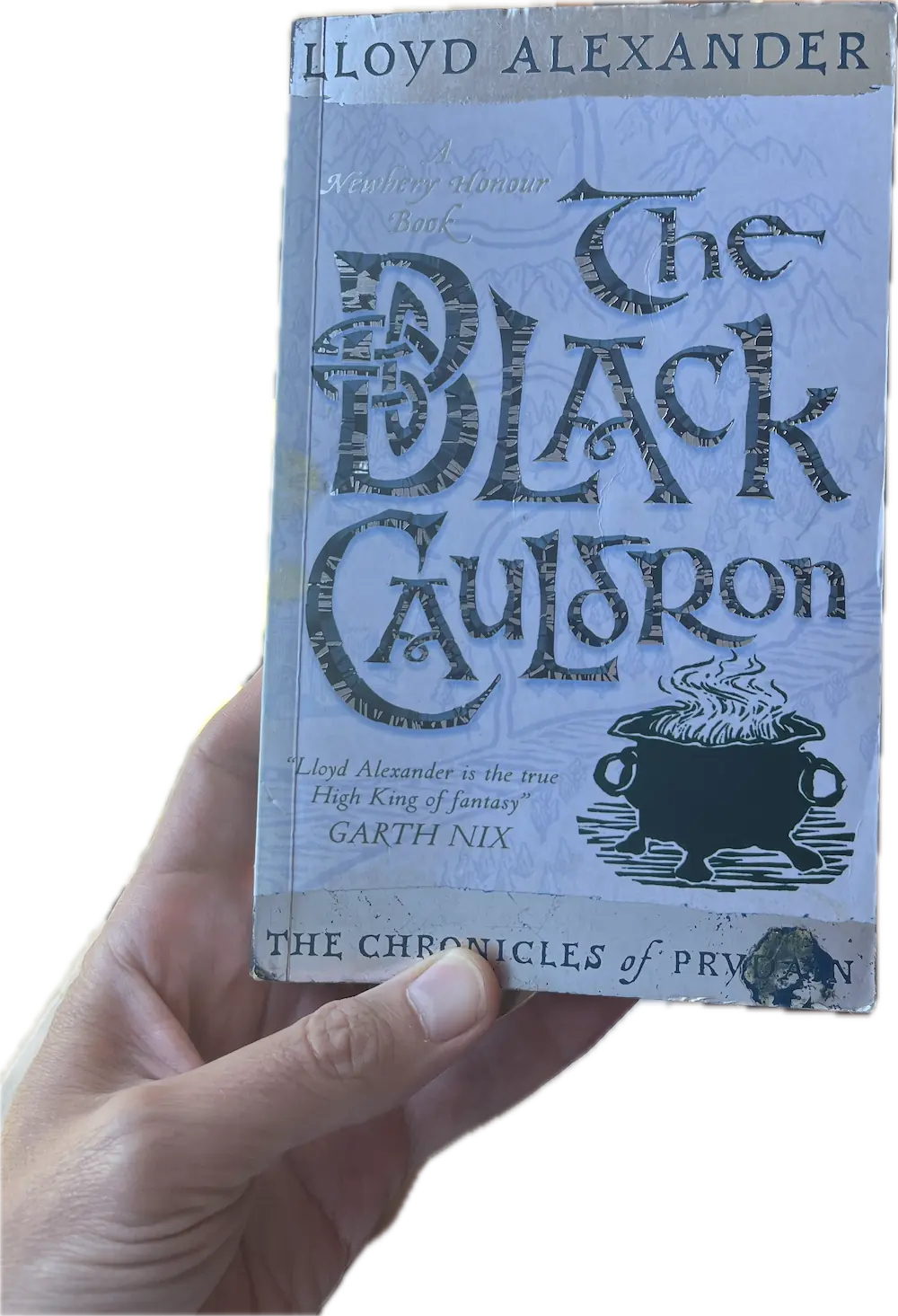 A hand holding a book, The Black Cauldron