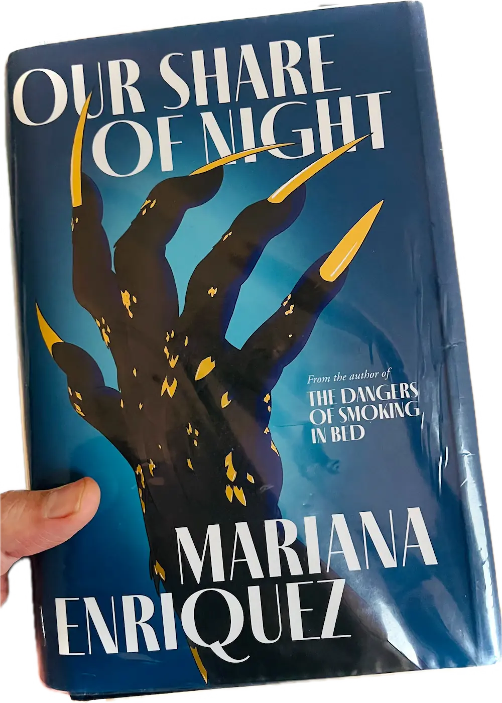 A hand holding a book, Our Share of Night
